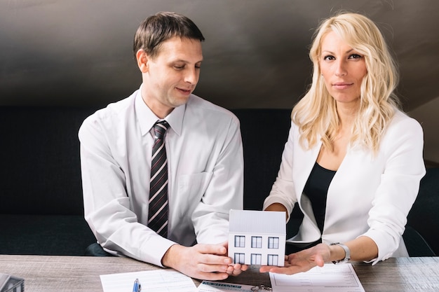 Confident people holding toy house together