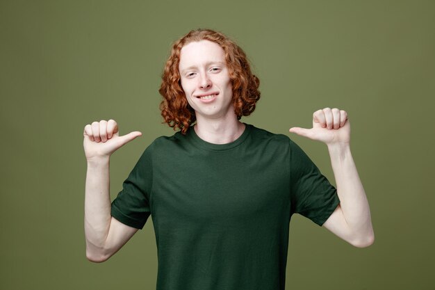 Confident points at himselfe young handsome guy wearing green t shirt isolated on green background