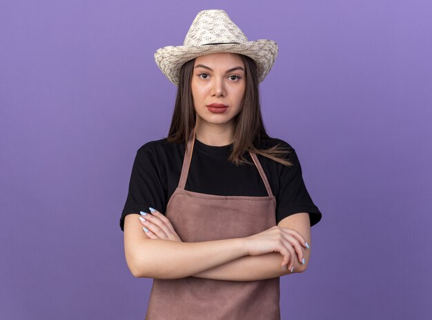 Confident pretty caucasian female gardener wearing gardening hat standing with crossed arms