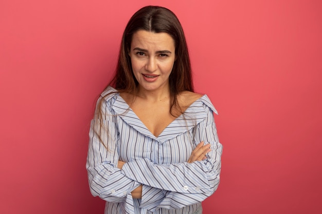 Confident pretty caucasian woman standing with crossed arms on pink