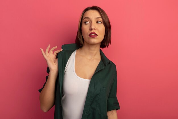 Confident pretty woman holds collar and looks at side isolated on pink wall