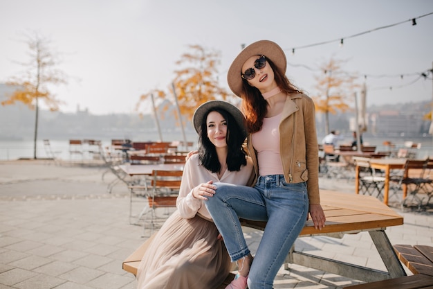 Confident red-haired woman in glasses sitting in cafe in autumn morning