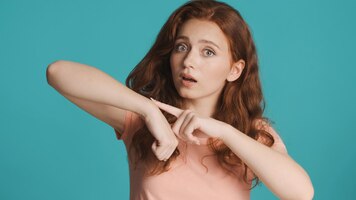 Free photo confident redhead girl pointing to wrist showing look at watch gesture on camera over colorful background hurry up expression