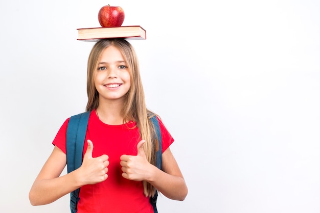 Free photo confident schoolgirl balancing book on head