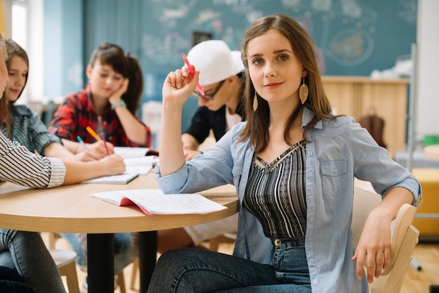 Confident schoolgirl at table with classmates