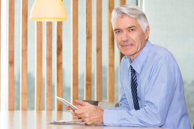 Confident senior businessman sitting with touchpad