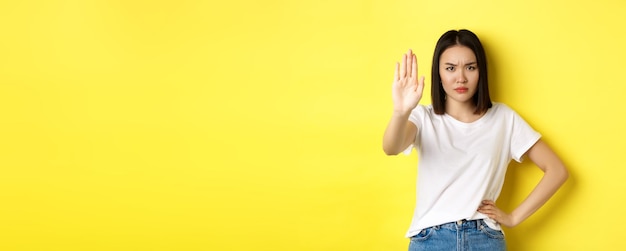 Confident and serious asian woman tell no showing stop gesture to prohibit and warn disagree with so