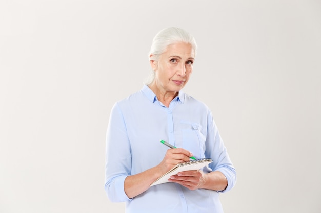 Confident serious woman writing in notebook isolated