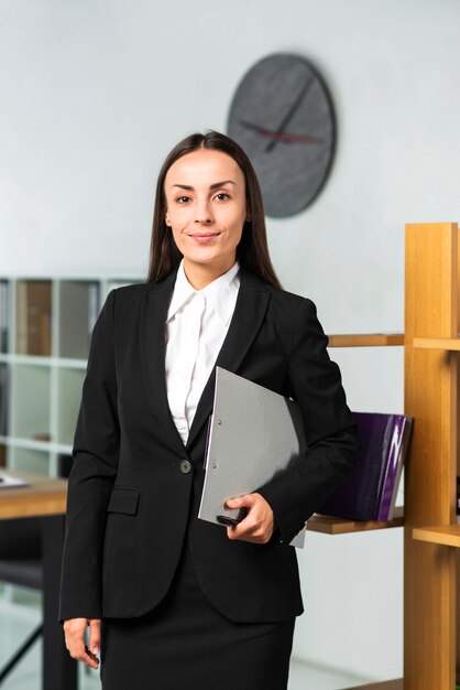 Confident smiling businesswoman holding clipboard and pen in hand