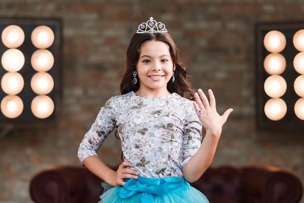 Confident smiling girl showing finger ring against stage light