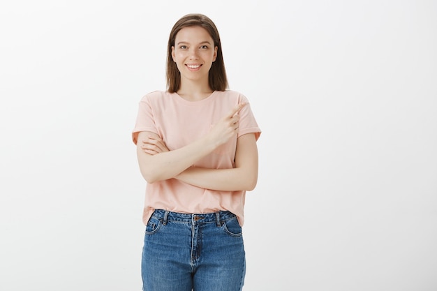 Confident smiling woman making choice, pointing upper right corner