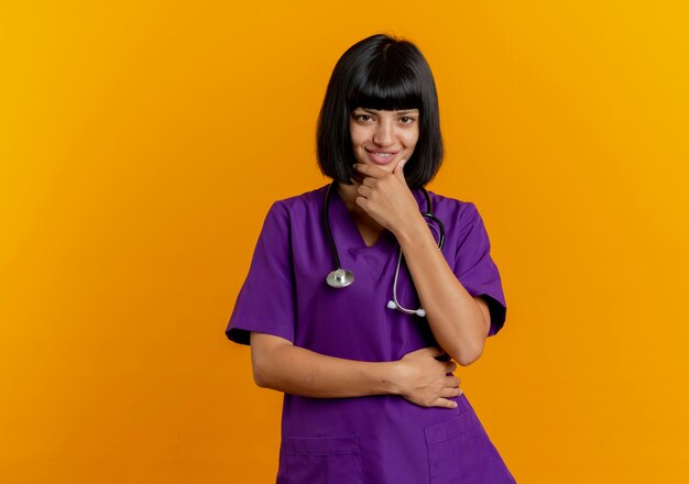 Confident smiling young brunette female doctor in uniform with stethoscope