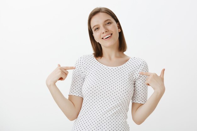 Confident smiling young woman student pointing at herself