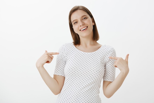 Confident smiling young woman student pointing at herself