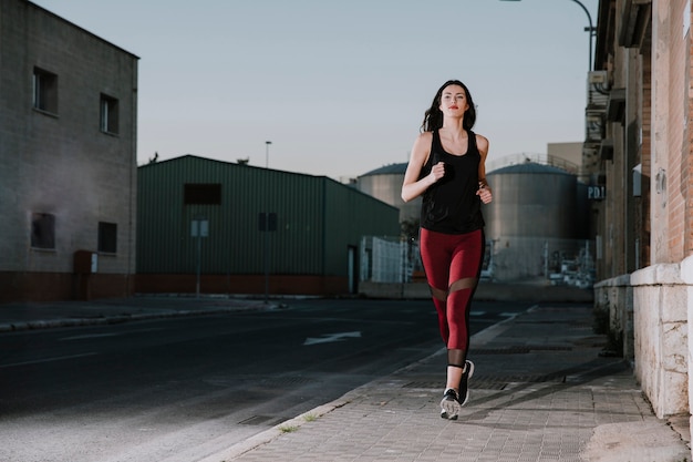 Confident sportswoman running on street