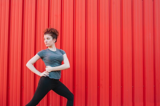 Confident sportswoman stretching on street