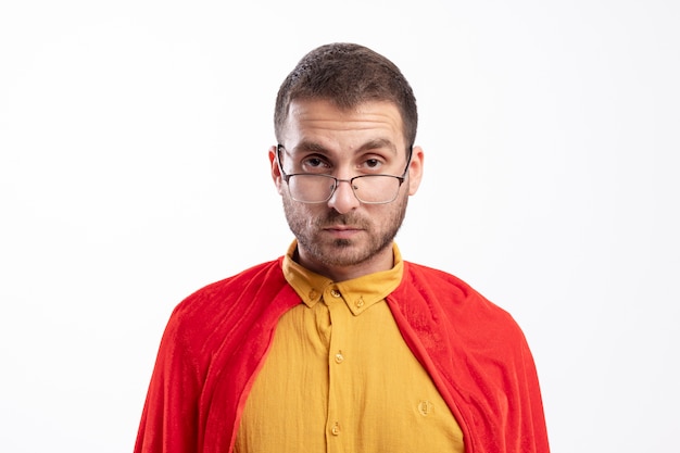 Free photo confident superhero man in optical glasses with red cloak looks at front isolated on white wall