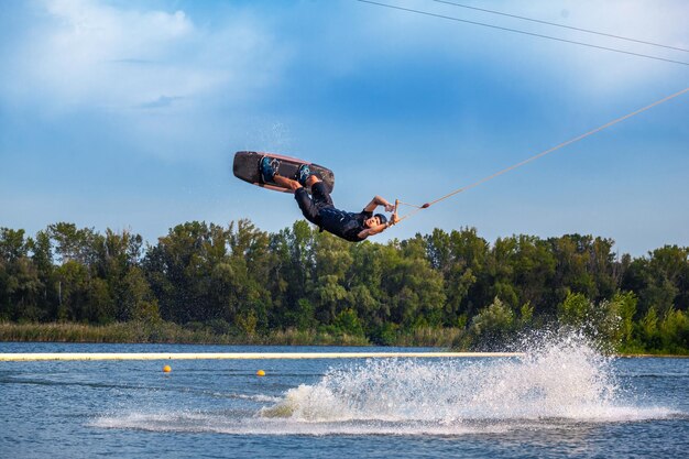 Confident wakeboard rider towed on cable showing tricks in open water
