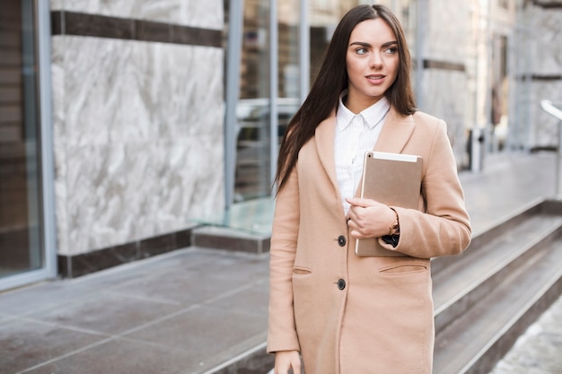 Donna sicura in cappotto con tavoletta