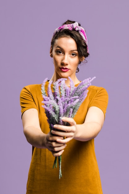 Foto gratuita donna sicura in vestito che tiene un mazzo di fiori di lavanda