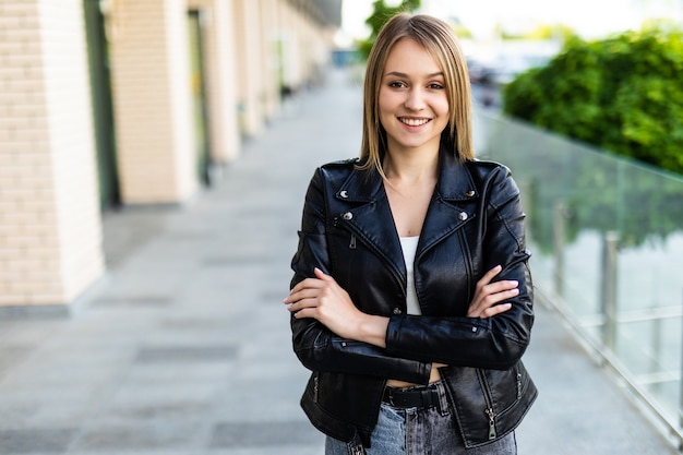 Confident woman looking at the camera while standing on the street with hands crossed