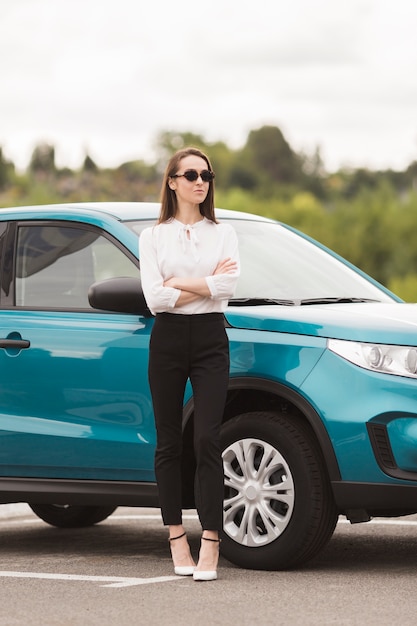 Confident woman posing in front of a car