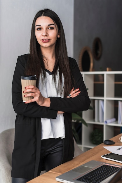 オフィスで飲み物を持つ自信のある女性