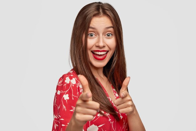 confident woman with red lipstick posing against the white wall