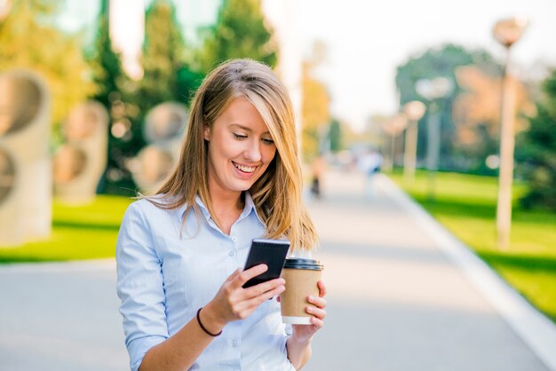 Confident women reading information about finance news while walking in company hallway during work break, successful businesswoman writing text message her client while goes with secretary to office