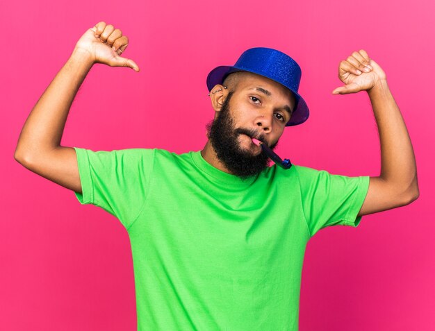 Free photo confident young afro-american guy wearing party hat points at himself