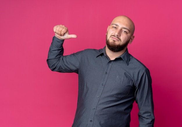 Confident young bald call center man pointing at himself isolated on crimson  with copy space