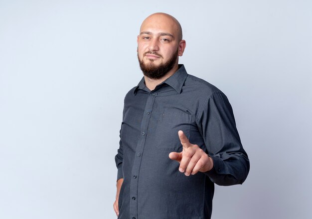 Confident young bald call center man putting hand on waist and pointing isolated on white  with copy space