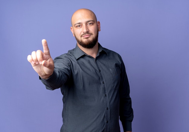 Confident young bald call center man raising finger isolated on purple  with copy space