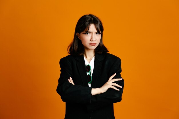 Уверенная молодая красивая женщина в черной куртке на оранжевом фоне