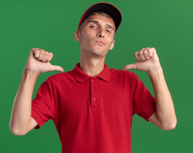 Confident young blonde delivery boy points at himself with two hands