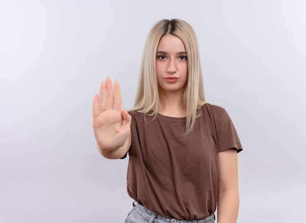 Confident young blonde girl stretching hand out  gesturing stop on isolated white space with copy space