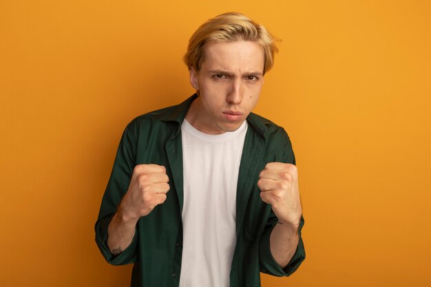 Confident young blonde guy wearing green t-shirt holding fists