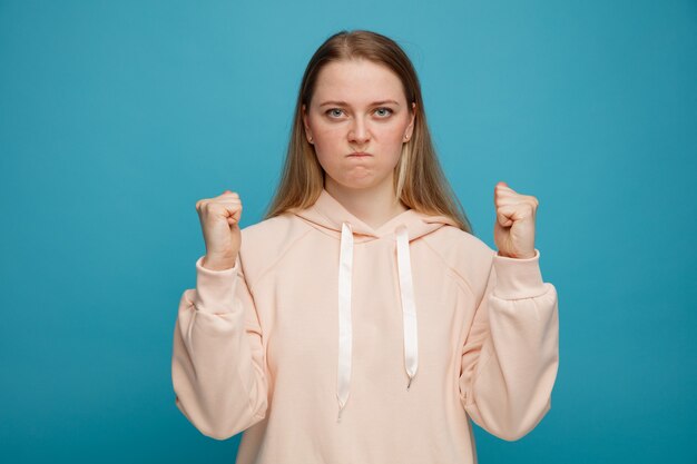 Confident young blonde woman clenching fists with pursed lips 