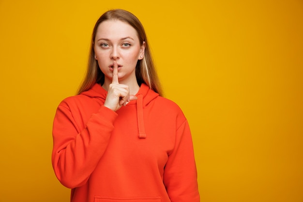 Confident young blonde woman doing silence gesture 