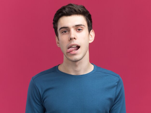 Confident young brunette caucasian boy stucks out tongue looking at camera