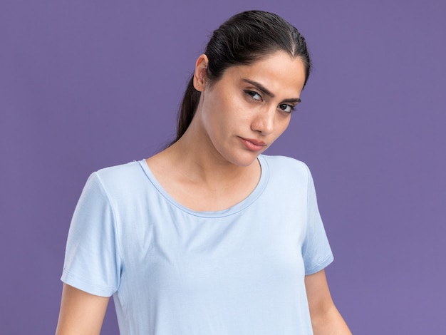 Confident young brunette caucasian girl looks at camera on purple background