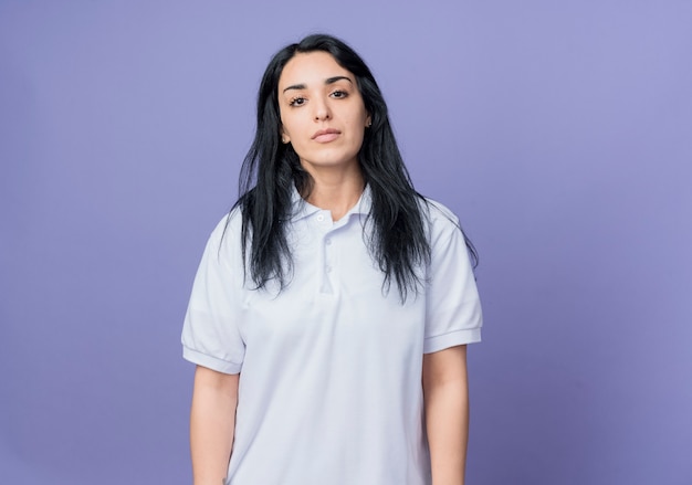 Confident young brunette caucasian girl stands isolated on purple wall