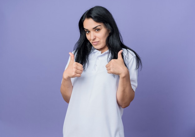 Confident young brunette caucasian girl thumbs up with two hands isolated on purple wall