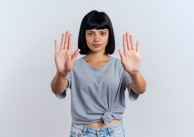 Foto gratuita i gesti fiduciosi della giovane donna caucasica castana fermano il segno della mano con due mani