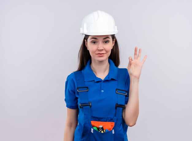 흰색 안전 헬멧 및 복사 공간이 격리 된 흰색 배경에 확인 파란색 유니폼 제스처와 확신 젊은 작성기 소녀