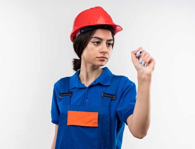 Confident young builder woman in uniform holding marker 