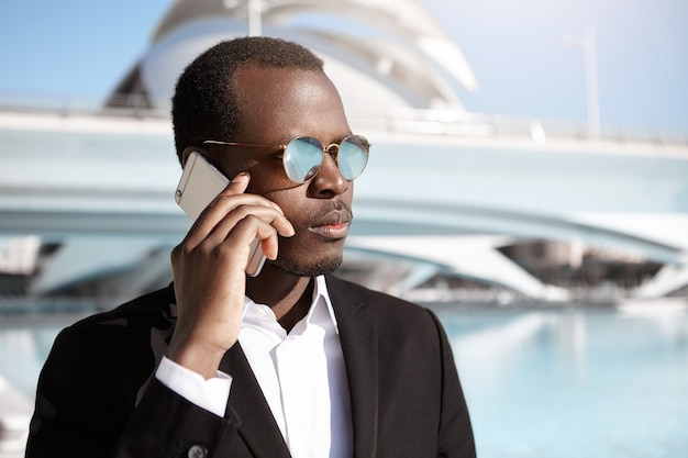 Confident young businessman having business negotiations on cell phone