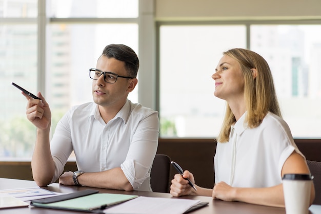 Confident young businessman showing presentation to smiling female colleague.