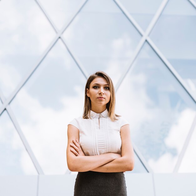 Confident young businessman standing in front of glass building