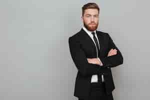 Free photo confident young businessman in suit standing with arms folded